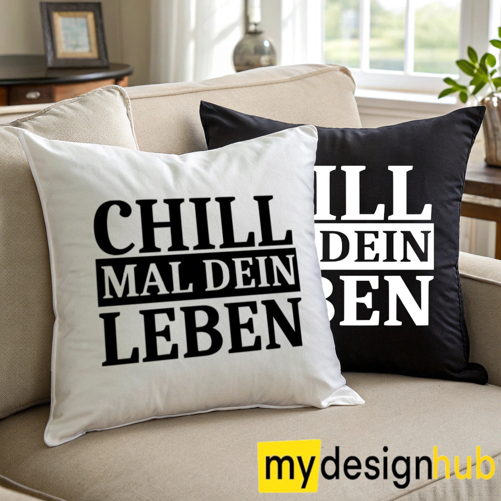 Weiße und schwarze Kissenbezüge mit Spruch „Chill mal dein Leben“ auf einem Sofa.