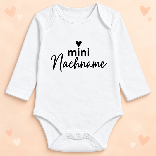Langarm-Babybody mini Herz – personalisierter Nachname mit dekorativem Hintergrund